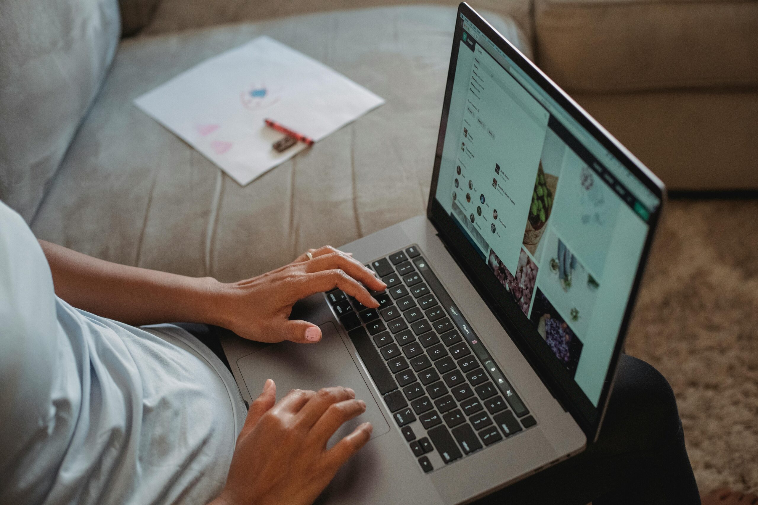 A person typing on a laptop at a wooden desk.